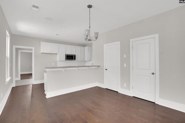 kitchen with hanging light fixtures, an inviting chandelier, kitchen peninsula, a breakfast bar, and white cabinets