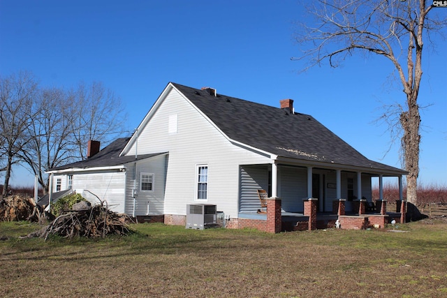 rear view of house with a porch, a garage, a yard, and central AC