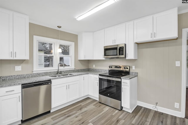 kitchen featuring appliances with stainless steel finishes, decorative light fixtures, white cabinetry, and sink