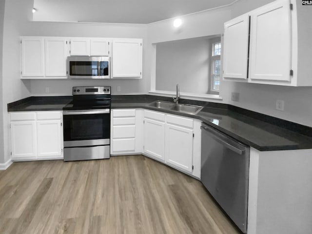 kitchen featuring appliances with stainless steel finishes, crown molding, sink, light hardwood / wood-style flooring, and white cabinets