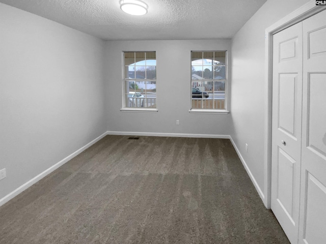 interior space featuring dark carpet and a textured ceiling