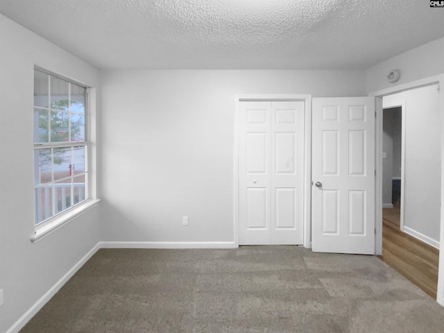 unfurnished bedroom with light carpet, a closet, and a textured ceiling