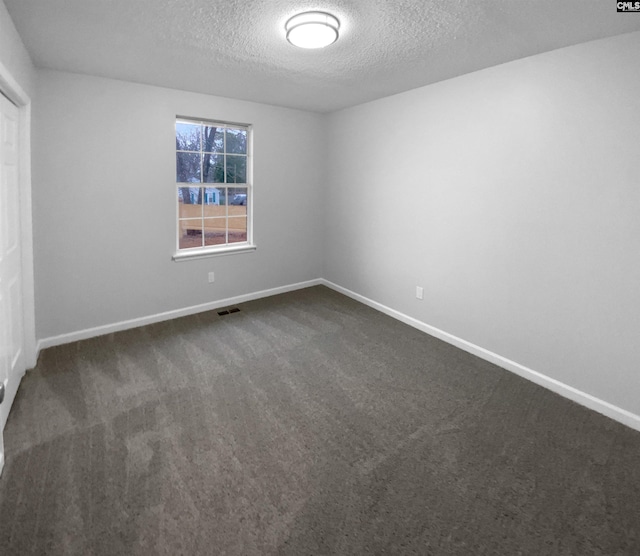 carpeted empty room featuring a textured ceiling