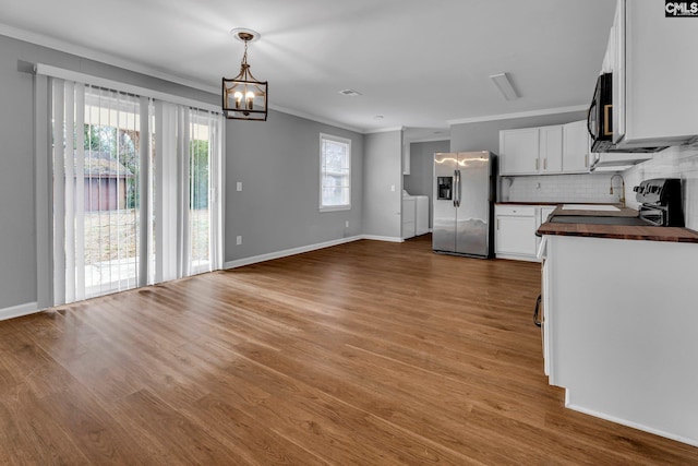 kitchen featuring wood counters, stainless steel fridge, tasteful backsplash, pendant lighting, and white cabinets