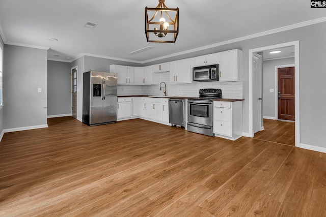 kitchen with white cabinets, decorative backsplash, stainless steel appliances, and sink