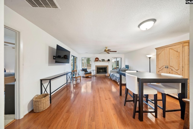 dining room featuring ceiling fan, light hardwood / wood-style floors, and a textured ceiling