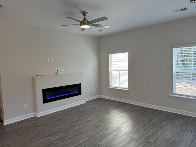 unfurnished living room featuring dark hardwood / wood-style floors, a wealth of natural light, and ceiling fan