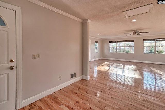 empty room with ceiling fan, ornamental molding, a textured ceiling, and light hardwood / wood-style flooring