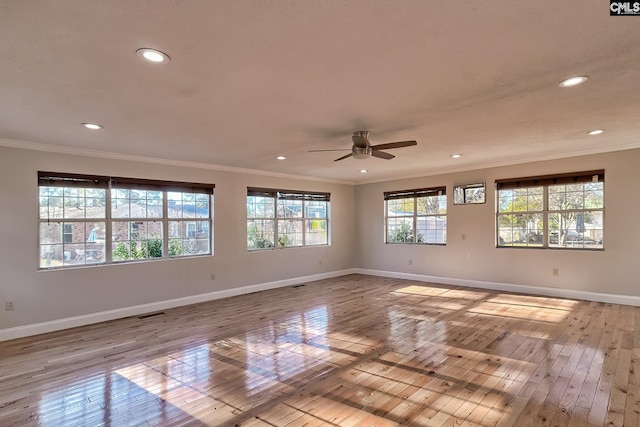 spare room featuring light hardwood / wood-style floors, ceiling fan, and a healthy amount of sunlight