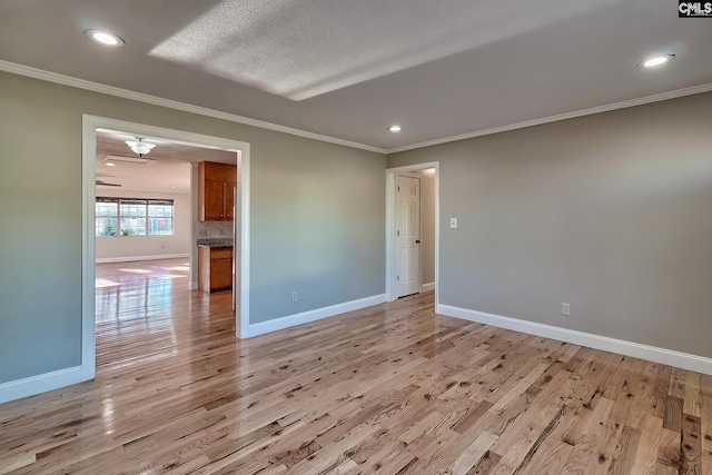 unfurnished room with a textured ceiling, light wood-type flooring, and crown molding