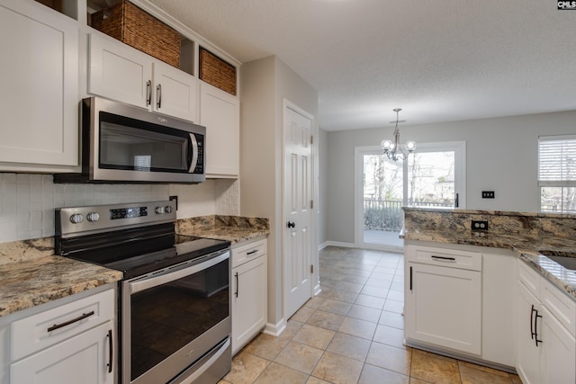 kitchen with pendant lighting, white cabinetry, stainless steel appliances, stone countertops, and a chandelier