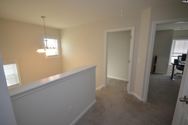 corridor featuring carpet flooring and a chandelier