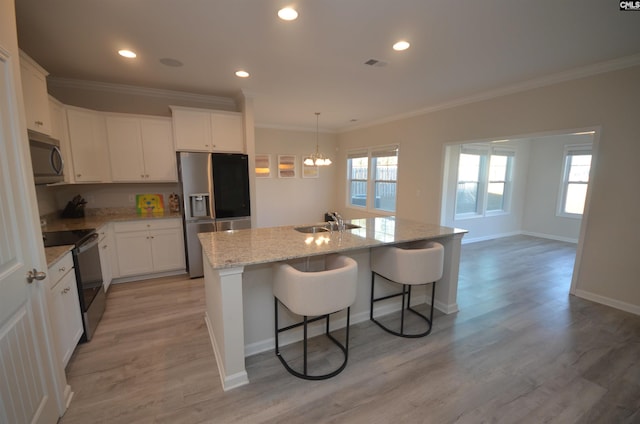 kitchen with appliances with stainless steel finishes, sink, light hardwood / wood-style floors, white cabinetry, and an island with sink