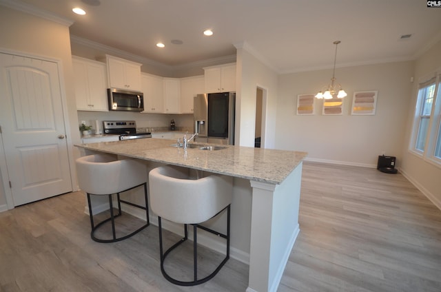 kitchen with white cabinets, sink, an island with sink, appliances with stainless steel finishes, and a notable chandelier