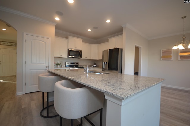 kitchen featuring a kitchen island with sink, white cabinets, sink, light hardwood / wood-style flooring, and stainless steel appliances