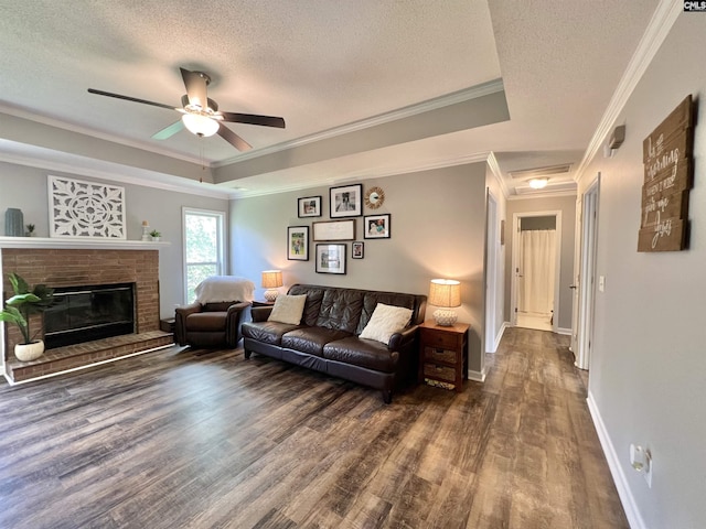 living room featuring a textured ceiling, a raised ceiling, ceiling fan, and crown molding