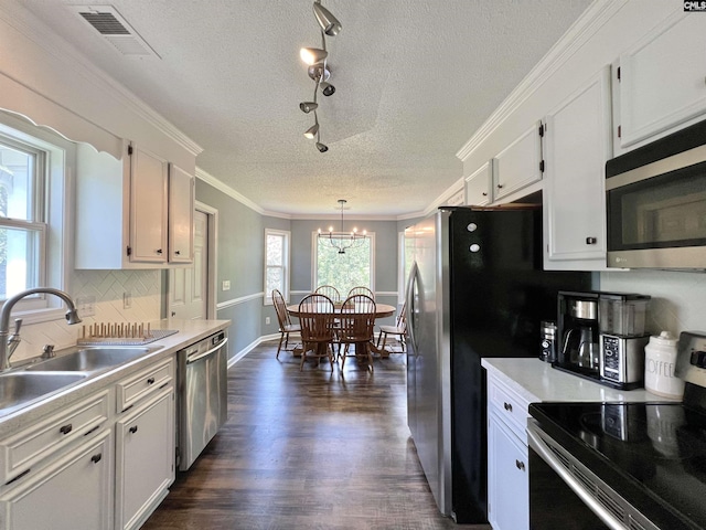 kitchen with white cabinets, stainless steel appliances, hanging light fixtures, and a notable chandelier