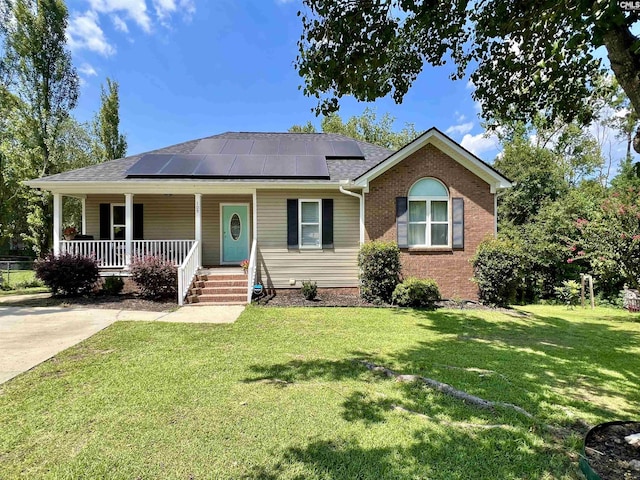 ranch-style home with covered porch, solar panels, and a front lawn