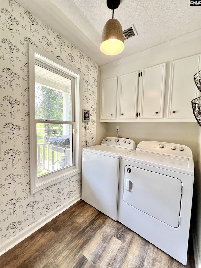 clothes washing area featuring cabinets, a textured ceiling, separate washer and dryer, and dark hardwood / wood-style floors