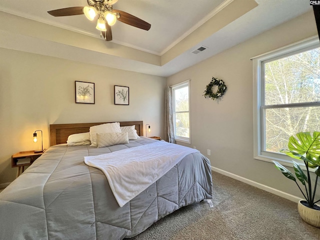 bedroom featuring carpet flooring, ceiling fan, multiple windows, and a tray ceiling