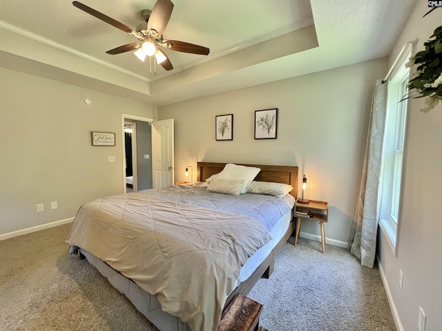 bedroom featuring ceiling fan, a raised ceiling, ornamental molding, and carpet floors