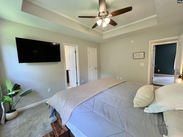 carpeted bedroom with a tray ceiling, ceiling fan, and ornamental molding