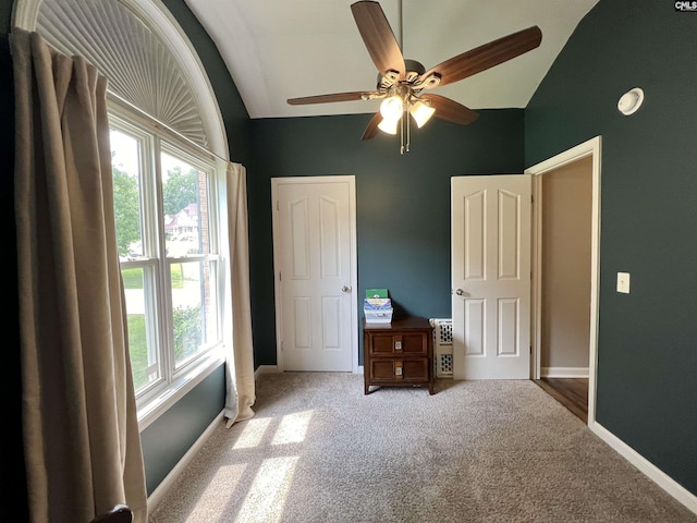 unfurnished bedroom with carpet, multiple windows, ceiling fan, and lofted ceiling