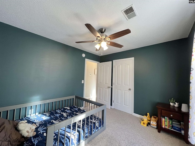 carpeted bedroom featuring ceiling fan and a textured ceiling