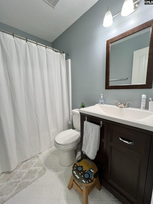 bathroom with vanity, toilet, and a textured ceiling