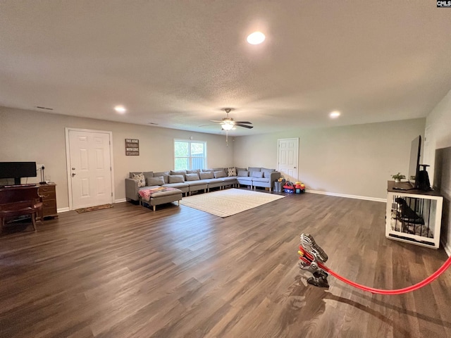 living room with a textured ceiling, dark hardwood / wood-style floors, and ceiling fan