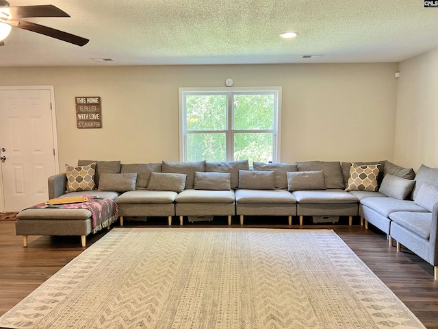 living room with ceiling fan, dark hardwood / wood-style flooring, and a textured ceiling