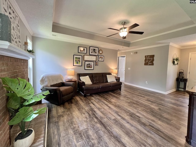 living room with a raised ceiling, ceiling fan, dark hardwood / wood-style floors, and ornamental molding