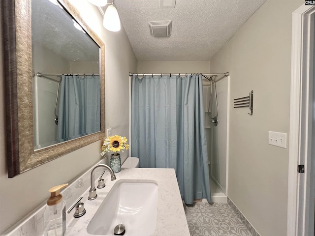 bathroom featuring a textured ceiling, vanity, and walk in shower