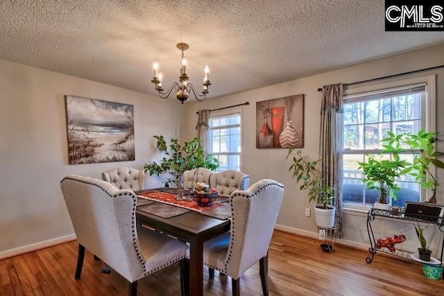 dining space featuring hardwood / wood-style floors, a textured ceiling, and a notable chandelier