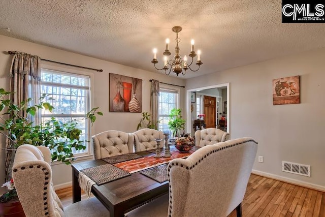 dining area featuring a chandelier, a textured ceiling, and light hardwood / wood-style flooring