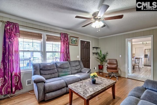 living room featuring ceiling fan, hardwood / wood-style floors, a textured ceiling, and ornamental molding