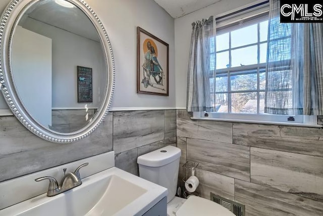 bathroom featuring vanity, toilet, tile walls, and a wealth of natural light