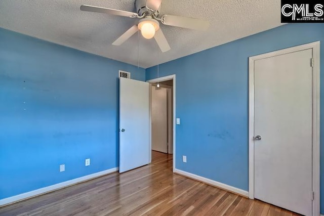 unfurnished bedroom with ceiling fan, a textured ceiling, and hardwood / wood-style flooring