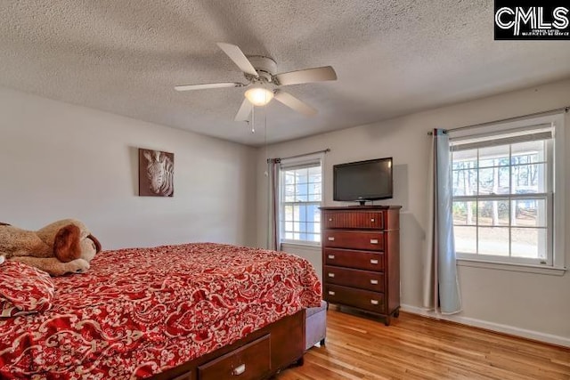 bedroom with ceiling fan, a textured ceiling, and light wood-type flooring