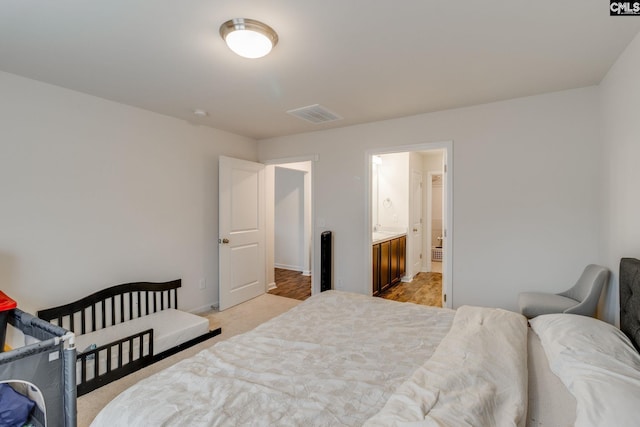 bedroom with ensuite bathroom and light hardwood / wood-style flooring