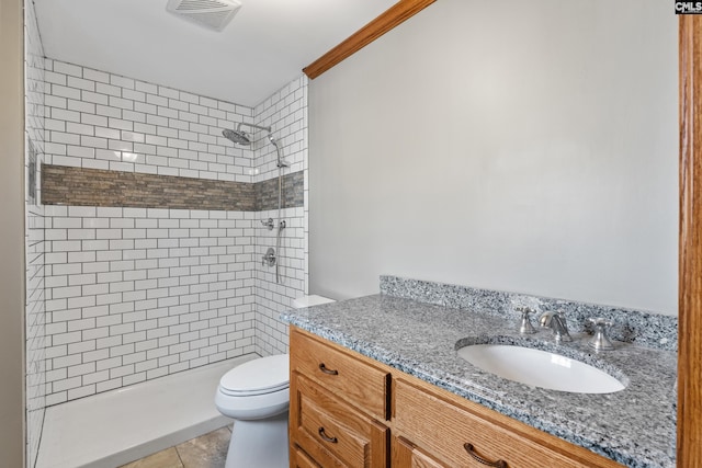 bathroom with vanity, tile patterned floors, toilet, ornamental molding, and a tile shower