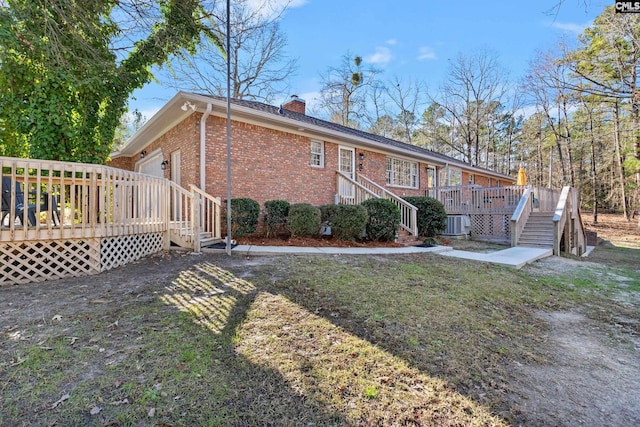 back of property with a deck, a yard, and central AC