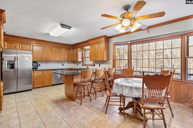 kitchen featuring kitchen peninsula, appliances with stainless steel finishes, a kitchen bar, ornamental molding, and sink