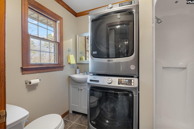 laundry room with sink, dark tile patterned flooring, stacked washer / drying machine, and ornamental molding