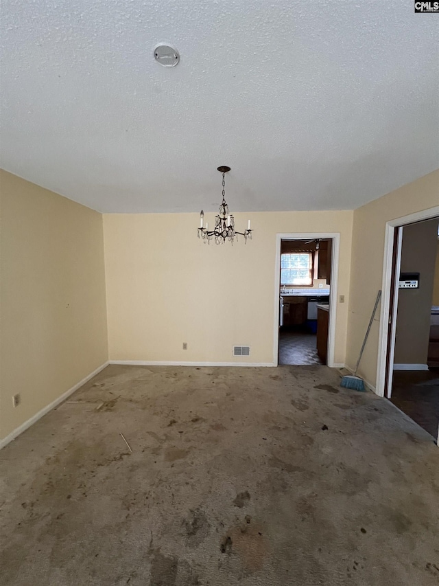 unfurnished dining area with dark colored carpet, a textured ceiling, and an inviting chandelier