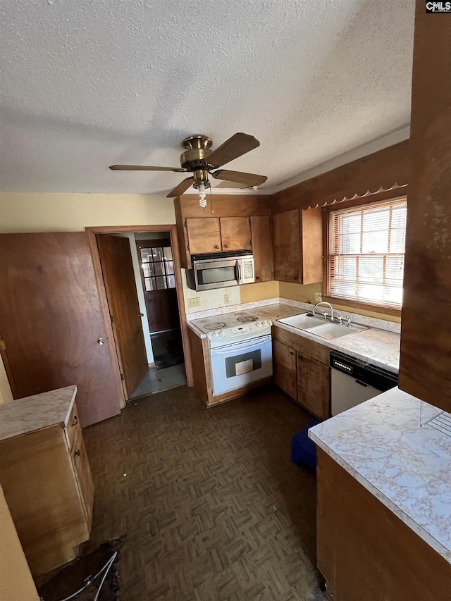 kitchen featuring appliances with stainless steel finishes, dark parquet floors, a textured ceiling, ceiling fan, and sink