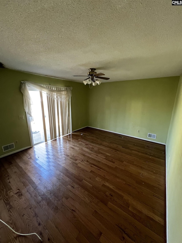 unfurnished room featuring ceiling fan, dark wood-type flooring, and a textured ceiling