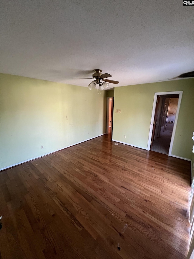 spare room featuring a textured ceiling, ceiling fan, and dark wood-type flooring