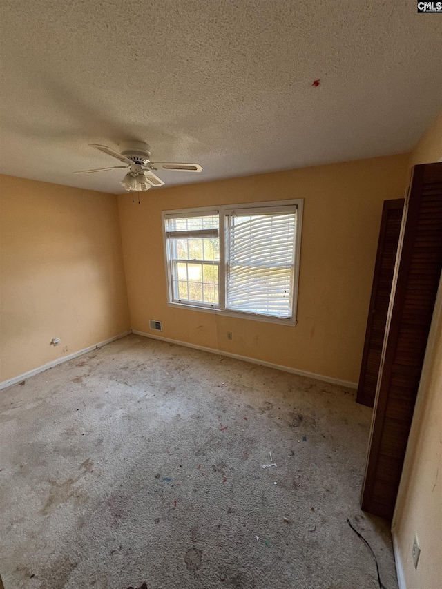 carpeted empty room with a textured ceiling and ceiling fan