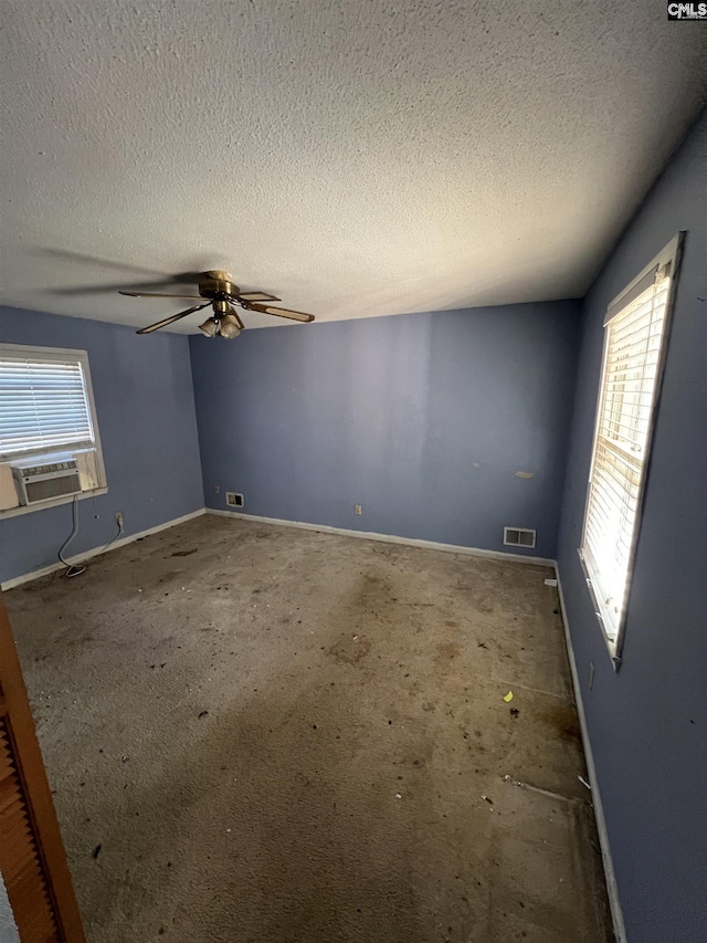 spare room featuring ceiling fan, cooling unit, and a textured ceiling